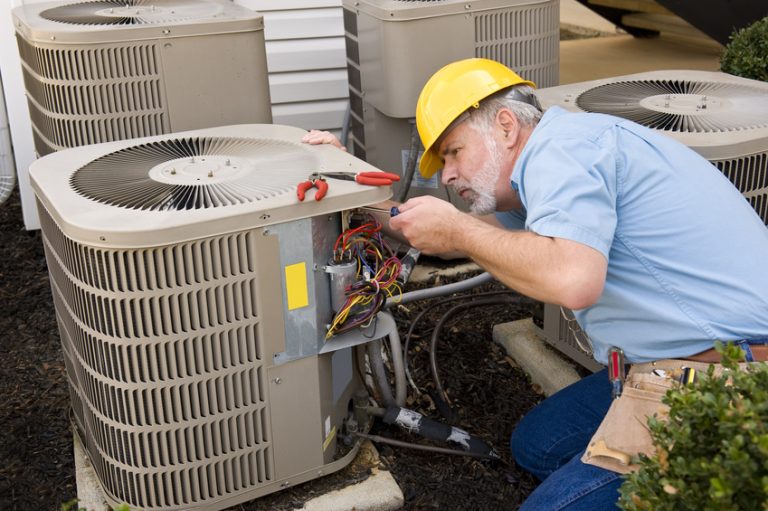 Technician servicing an outdoor air conditioner condenser